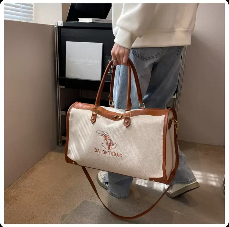 ساک ورزشی و سفری اسپرت وارداتی مدل ربیت کانواس (Rabbit Canvas)، کرم با جزئیات چرمی مشکی و قهوهای، دارای بند دوشی قابل تنظیم و آستر داخلی